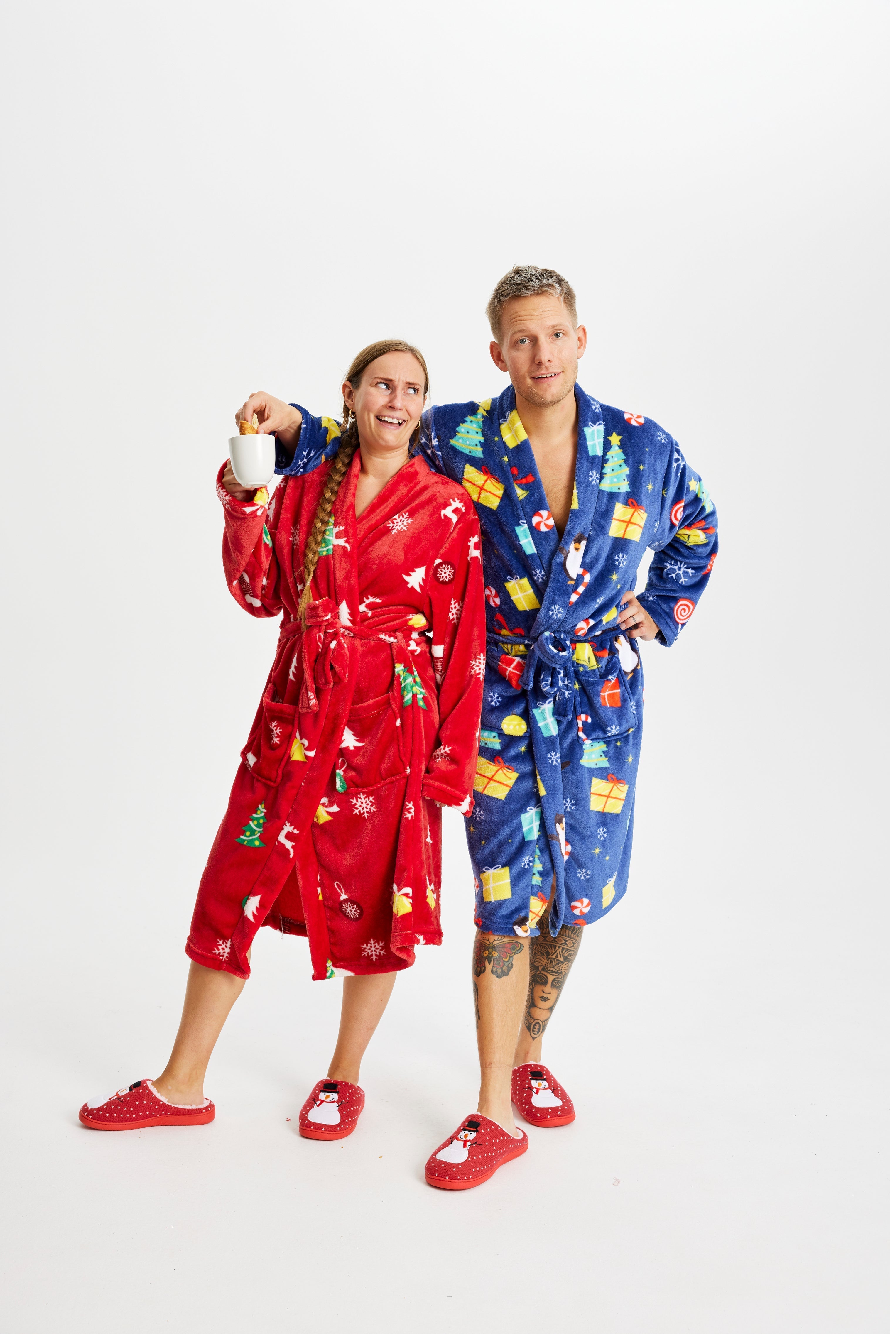 Een koppel dat elk een bedrukte kerstbadjas draagt.
